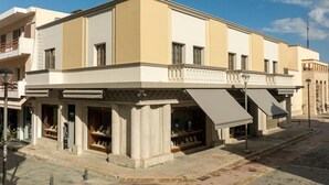 Ein zweistöckiges Gebäude mit flacher Fassade, großen Fenstern und einem überdachten Außenbereich mit Schaufenstern.