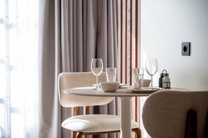 A dining area with a round table, two chairs, and a set of wine glasses and water glasses. - Volaka Luxury Suites `Sapphire` (Kos)