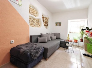 A living room with a grey sofa, a small ottoman, a coffee table, and a wall with a stone-like texture.