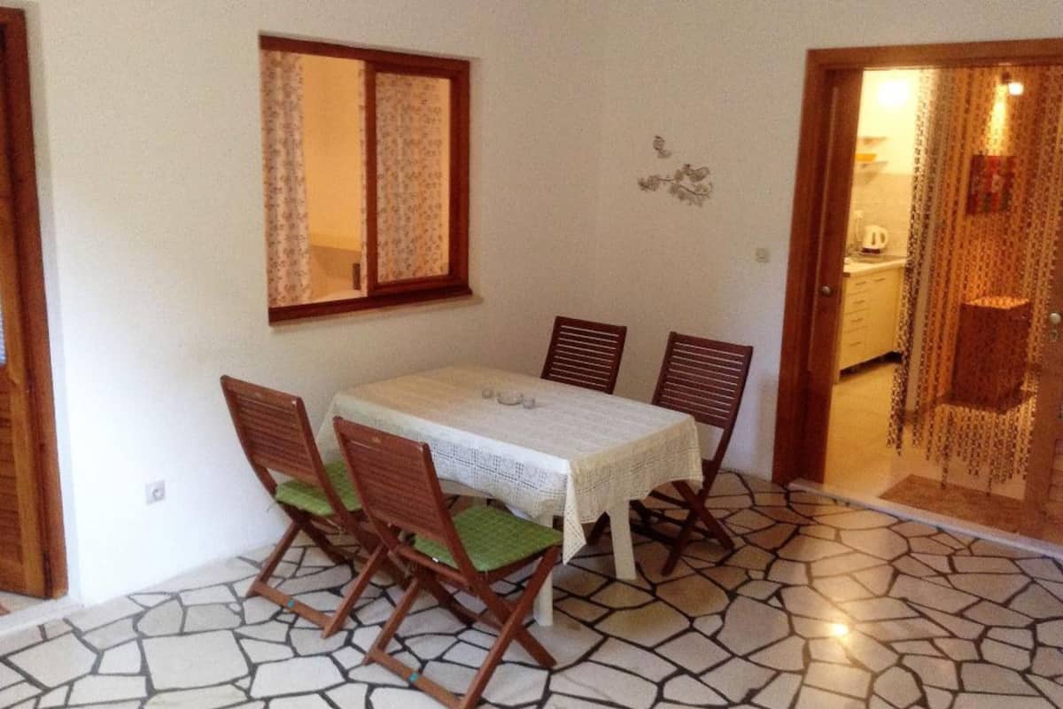Un comedor con mesa y sillas, una ventana con cortinas y piso de baldosas.