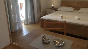 Une chambre avec un lit en bois, une table de chevet, une lampe et une vue sur un balcon.