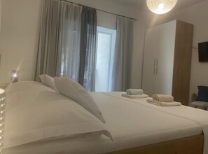 Una habitación de hotel con cama, armario, escritorio y televisor.