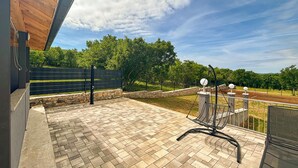 Un patio con una silla de metal, un muro de piedra y una terraza de madera.