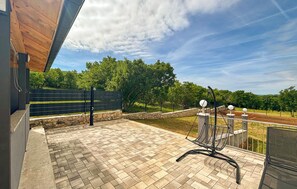 A patio with a metal chair, a stone wall, and a wooden deck. - Stunning home in Sinj (Sinj)