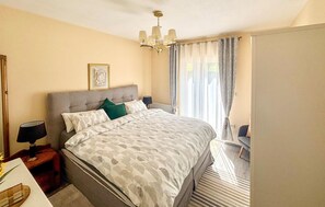A bedroom with a bed, bedside tables, a chandelier, curtains, and a framed picture on the wall. - Stunning home in Sinj (Sinj)