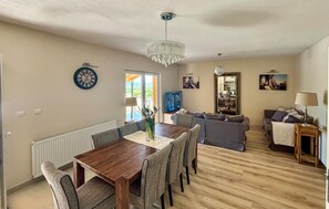 A spacious living area with a wooden dining table, grey sofas, a chandelier, and a television. - Stunning home in Sinj (Sinj)