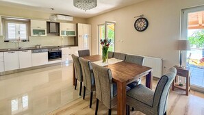 Una cocina moderna con comedor, un reloj en la pared y vistas al exterior.