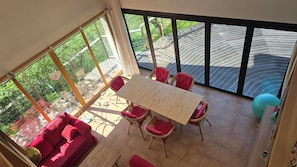 Ein sonnendurchflutetes Zimmer mit einem großen Tisch, roten Stühlen und einem roten Sofa.