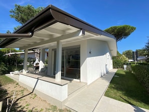 Ein modernes Haus mit überdachter Terrasse, Garage und gepflegtem Rasen.