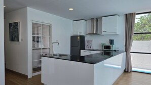 A modern kitchen with a black countertop, white cabinets, a stainless steel sink, a microwave, and a gas stove. - Gorgeous 4-bedroom house with AC in charming Chiang Mai (Chang Wat Chiang Mai)