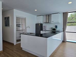 Eine moderne Küche mit schwarzem Arbeitsplatz, weißen Schränken, einer Edelstahl-Spüle, einer Mikrowelle und einem Gasherd.