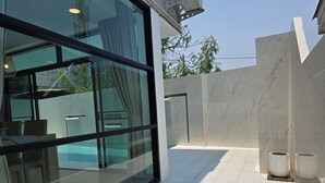 A modern outdoor area with a glass wall, a pool, and a tiled floor. - Gorgeous 4-bedroom house with AC in charming Chiang Mai (Chang Wat Chiang Mai)