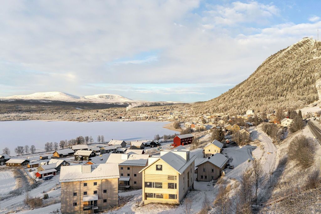 Une petite ville avec des bâtiments, un lac et une montagne en arrière-plan.