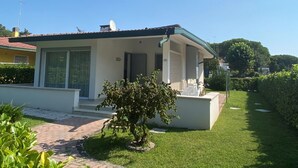 Een gelijkvloers huis met een overdekte veranda, een schotelantenne en een kleine tuin.