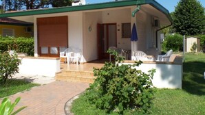 Een gelijkvloers huis met een overdekte veranda, een schotelantenne en een kleine tuin.