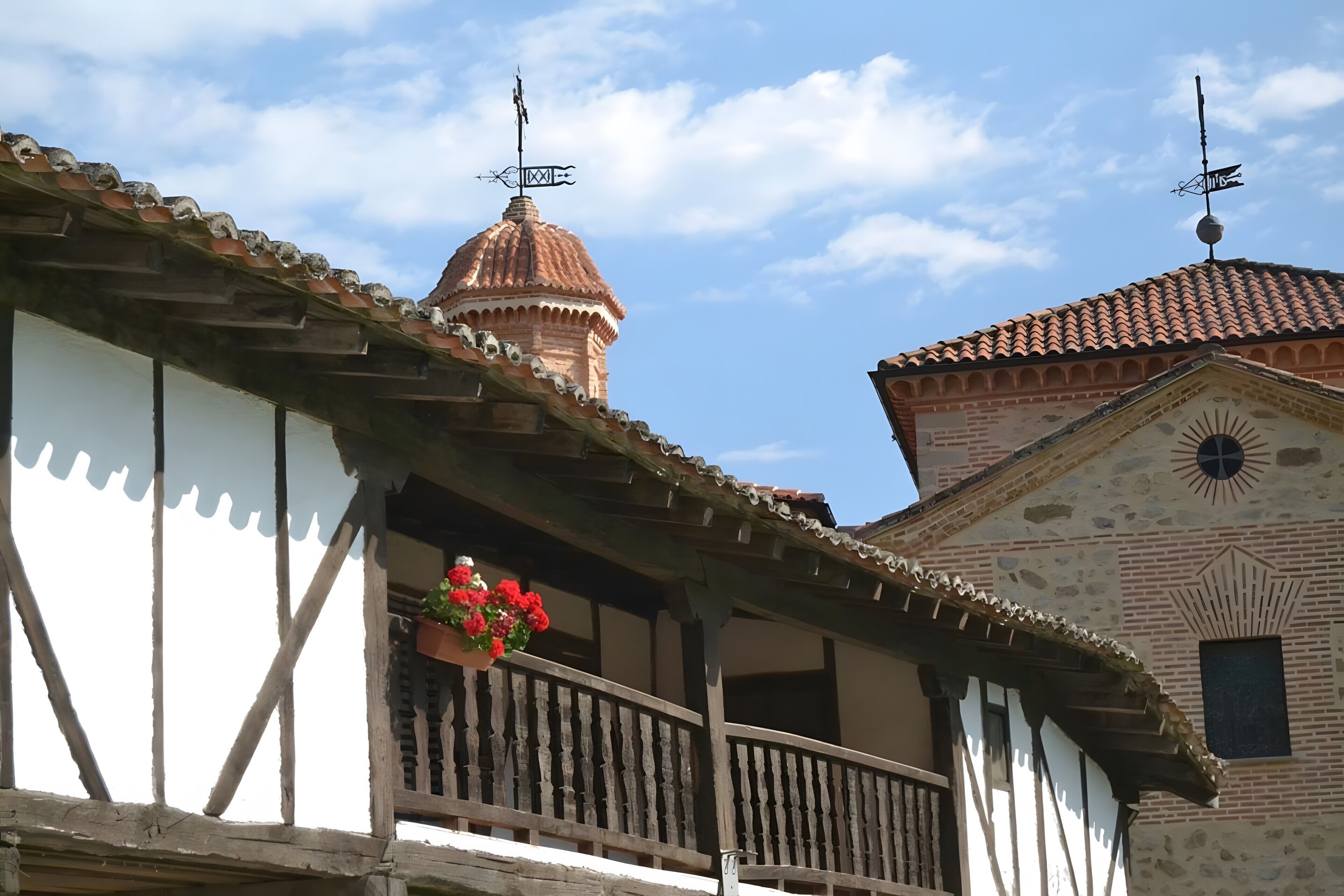 A traditional building with a balcony, a red dome, and a weather vane.
