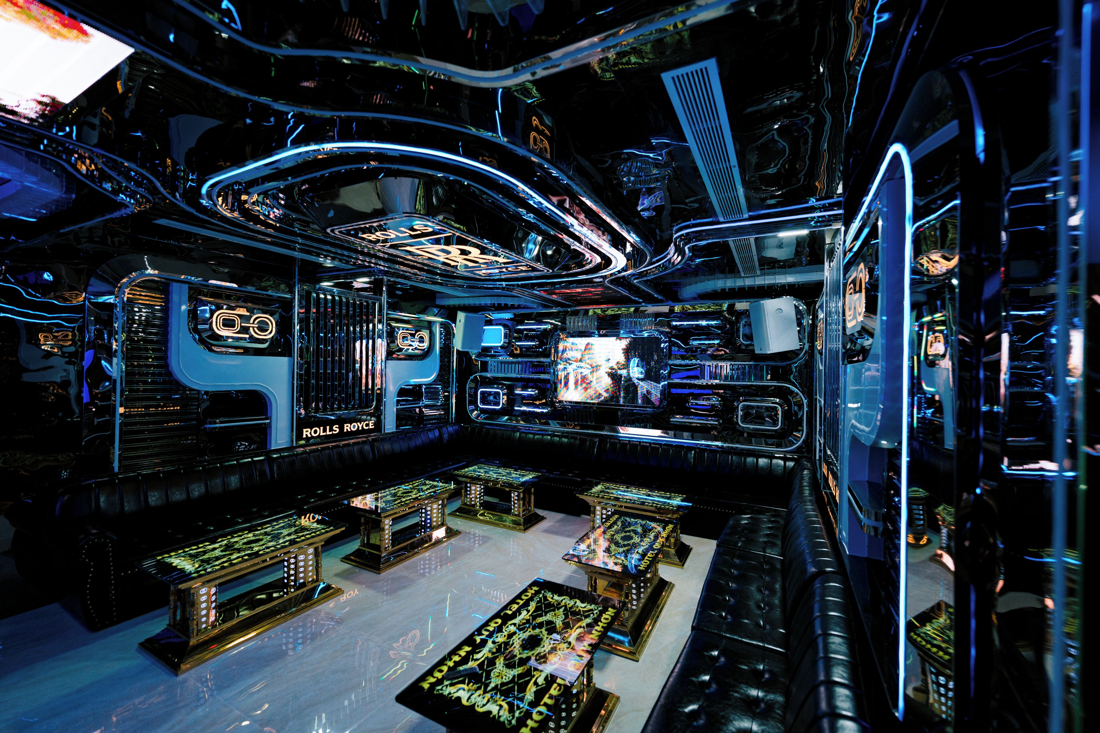 A futuristic interior with a central control panel, seating areas, and a neon-lit ceiling.