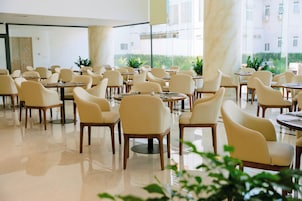 Un comedor amplio con múltiples mesas y sillas, ventanas grandes que dan a zonas verdes y un interior limpio y moderno.