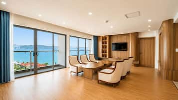Un salón moderno con una gran mesa de comedor, asientos cómodos, un televisor de pantalla plana y vistas al mar.