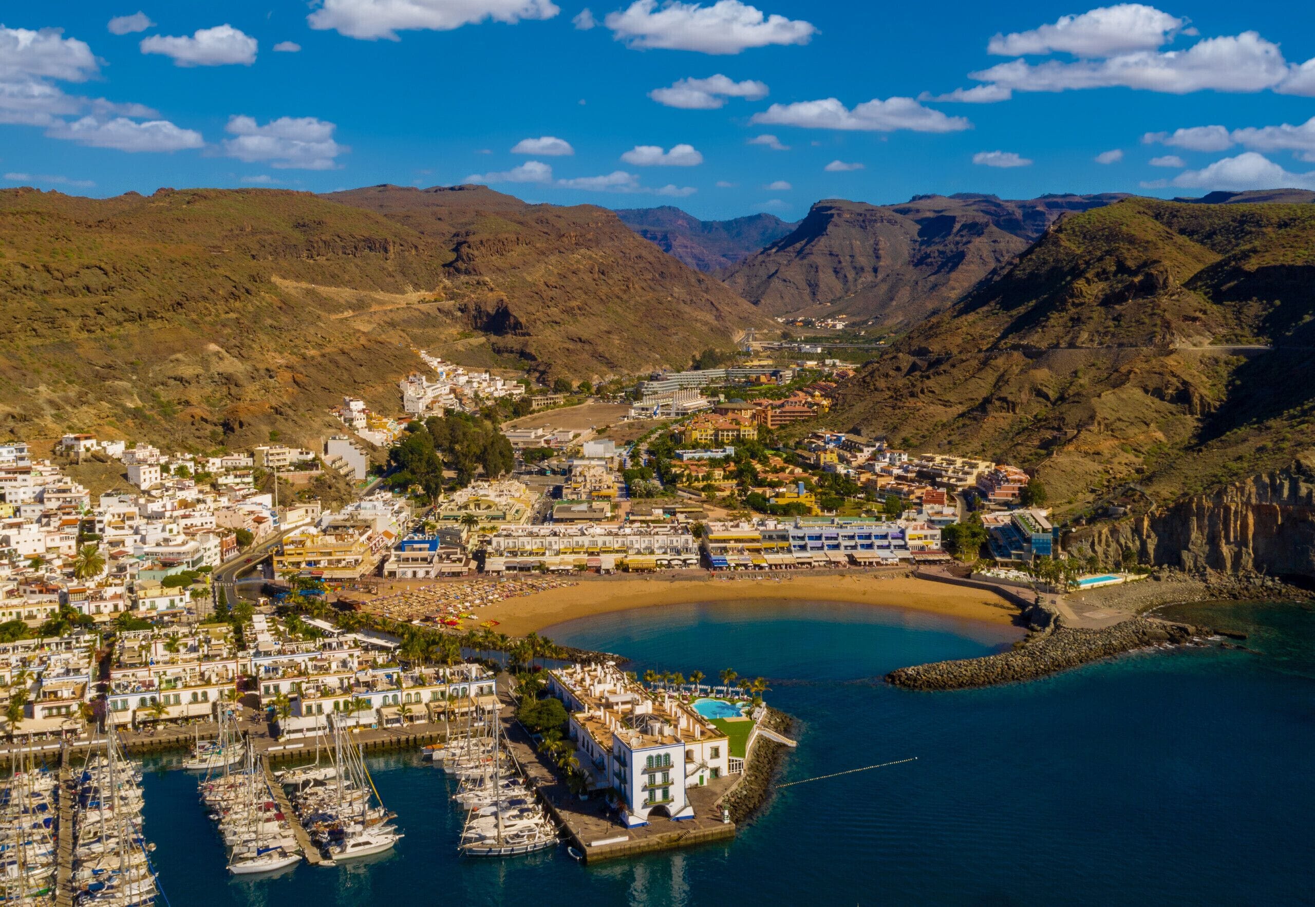 Une ville côtière dotée d’un port de plaisance, de bâtiments et, en arrière-plan, de montagnes.