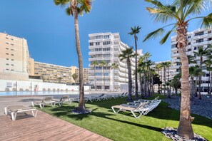 Ein Hotel mit Poolanlage, Palmen und einem modernen Gebäude im Hintergrund.