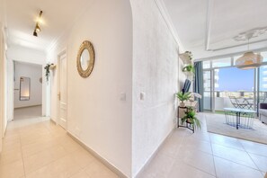 Ein geräumiger Flur mit einem runden Spiegel, einer Tür und Blick auf einen Balkon mit Tisch und Stühlen.
