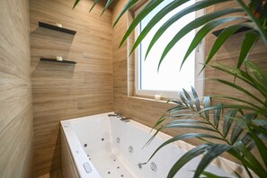 Un bagno moderno con una vasca freestanding, pareti in legno e una finestra.