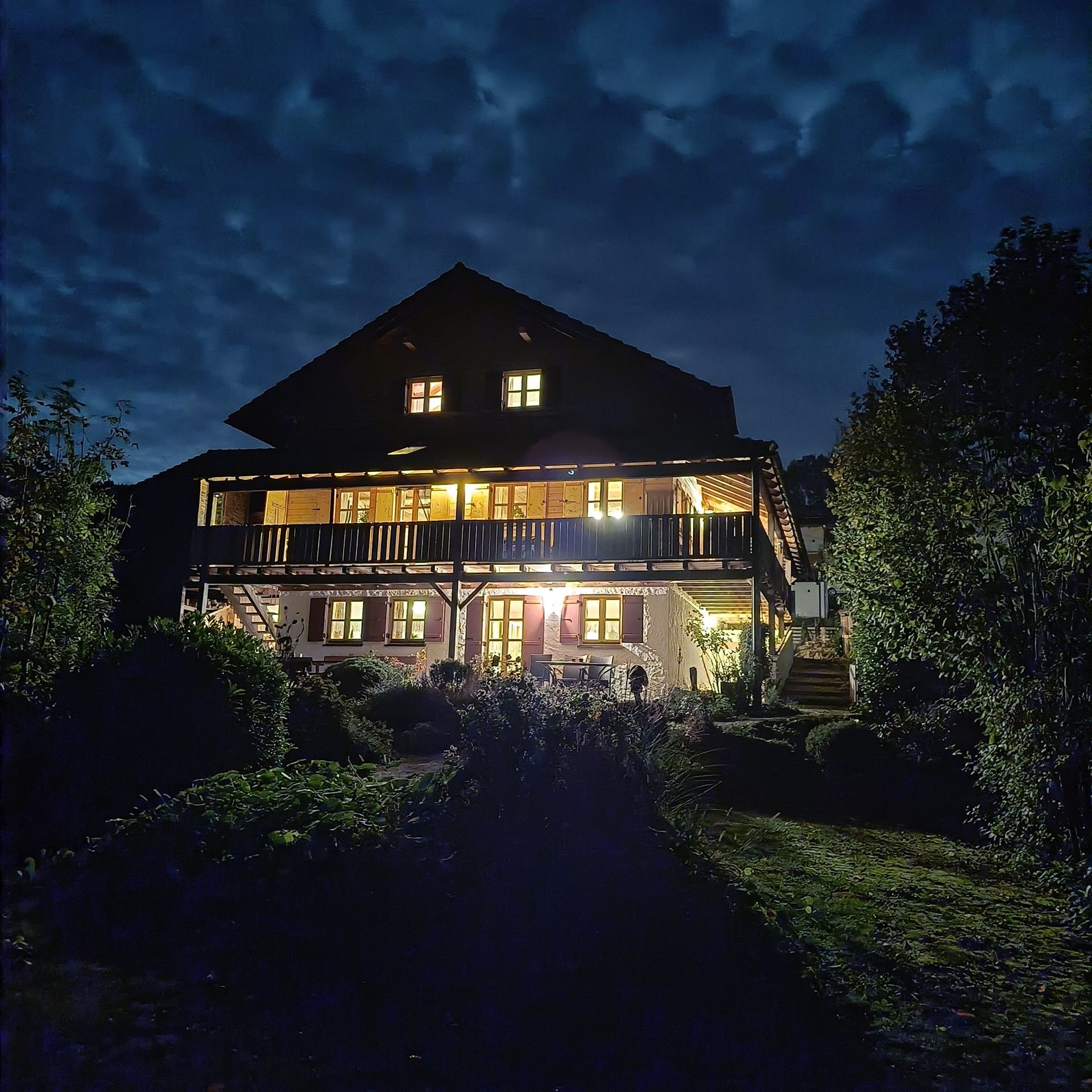 A two-story building with a balcony, a staircase, and a well-lit entrance.
