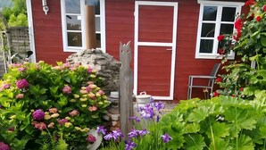 A red house with a pond, surrounded by various plants and flowers. - Landblick Lalling Apartment with Private Terrace, Garden, and Wi-Fi (Lalling)