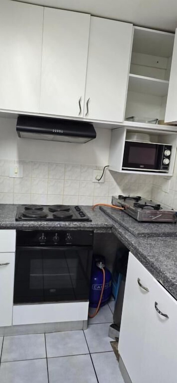 Uma cozinha com armários brancos, fogão preto, micro-ondas e fogão a gás.