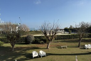 Una zona verde all'aperto con sedie bianche, una panchina e alberi.