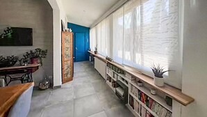 A hallway with a radiator, a blue door, and a bookshelf with books and a plant. - Lovely home in Lanton (Lanton)