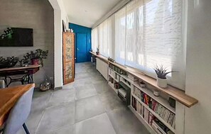 A hallway with a radiator, a blue door, and a bookshelf with books and a plant. - Beautiful home in Lanton (Lanton)