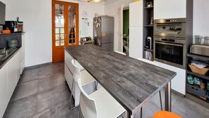 A modern kitchen with a central island, white cabinetry, and stainless steel appliances. - Lovely home in Lanton (Lanton)
