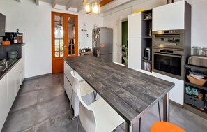 A modern kitchen with a central island, white cabinetry, and stainless steel appliances. - Beautiful home in Lanton (Lanton)