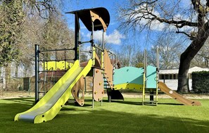 A playground with a slide, climbing structures, and a swing set. - Cozy (sta)caravan in Aureilhan (Aureilhan)