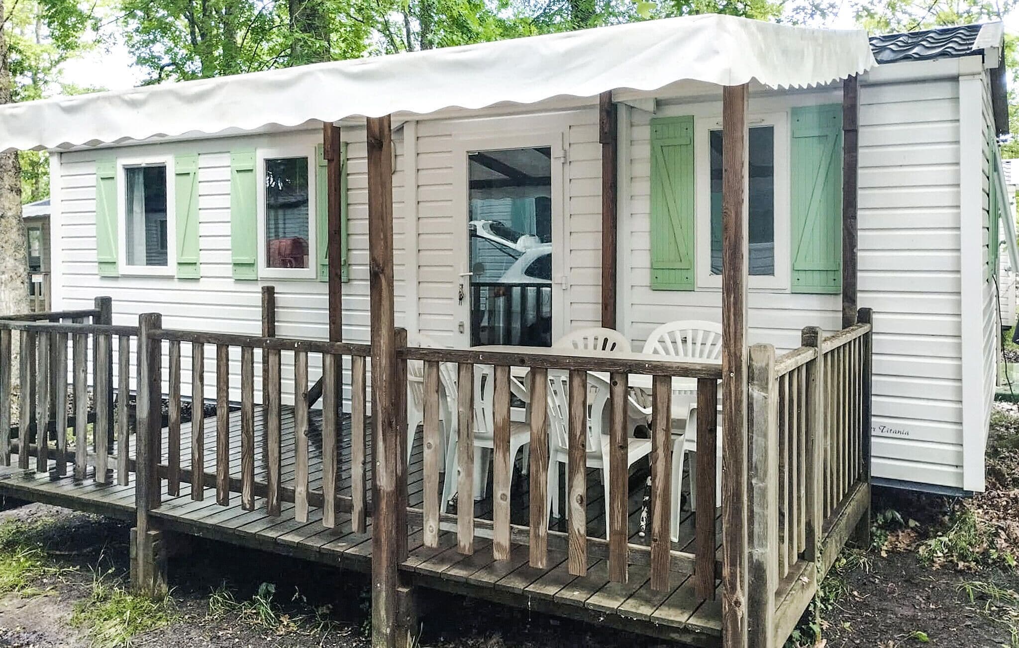 A small, single-story cabin with a wooden deck and a covered porch.