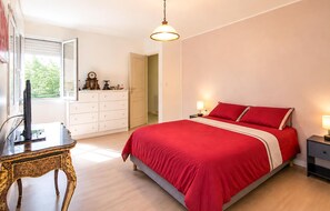 Ein Schlafzimmer mit Bett, Kommode, Fernseher und Fenster.