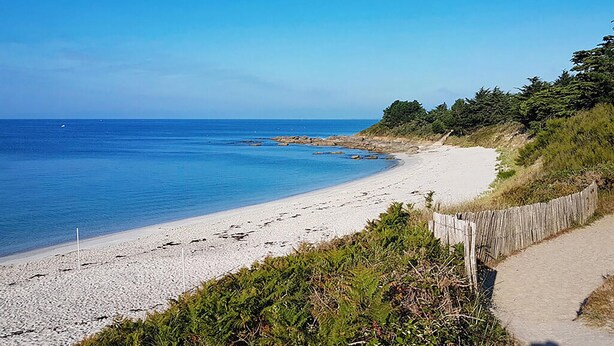 A beach with a wooden fence, clear blue water, and a rocky outcrop. - 3 bedroom amazing home in Saint-Yvi (Saint-Yvi)
