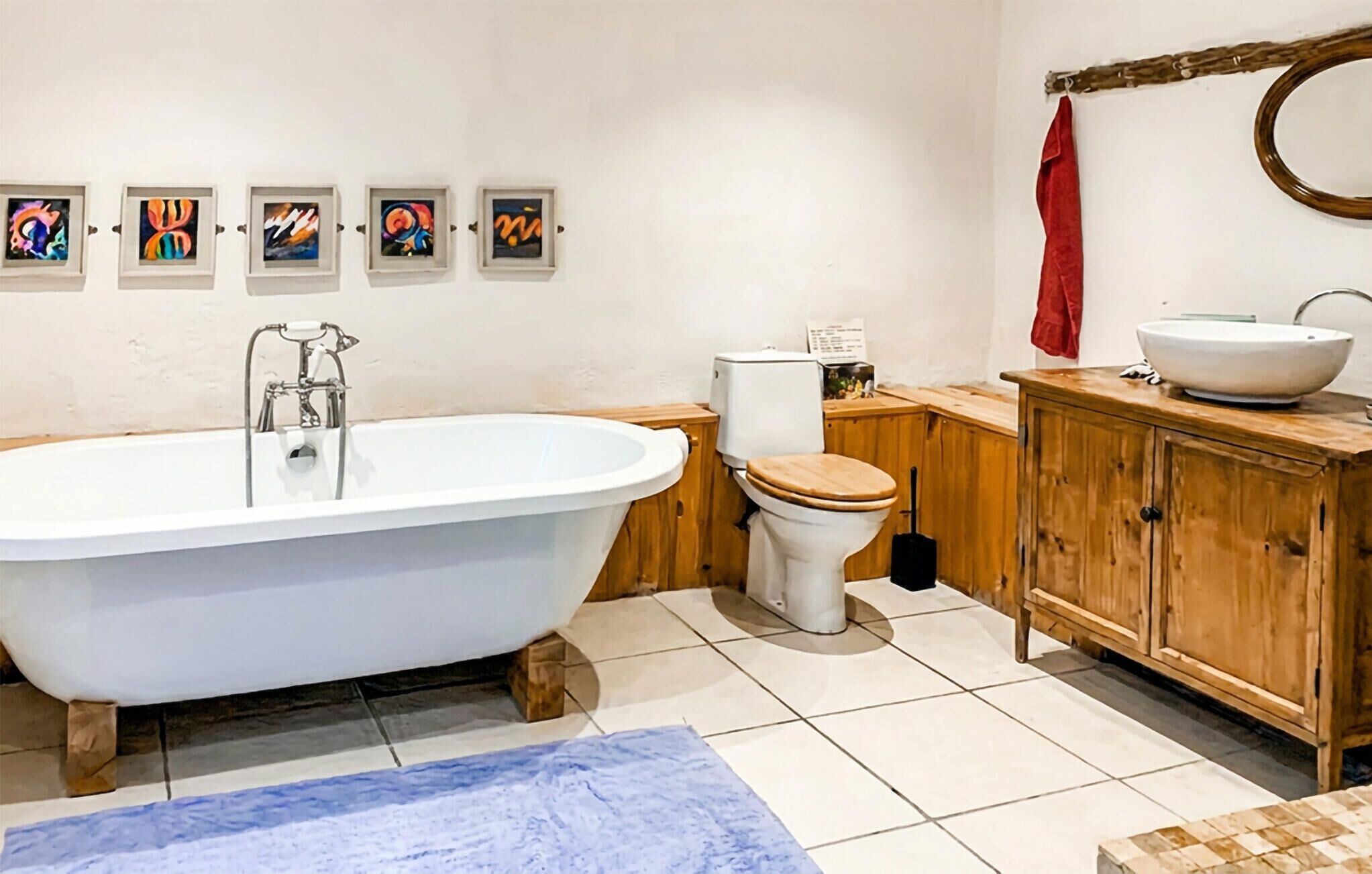 A bathroom with a freestanding bathtub, a toilet, a wooden cabinet, and a sink.