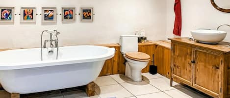 A bathroom with a freestanding bathtub, a toilet, a wooden cabinet, and a sink.