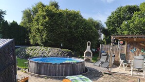 A backyard with a hot tub, a wooden swing, and a barbecue grill. - Relax under thatch with pool, beach chairs and loungers (Belum)