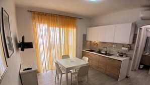 A compact living space with a dining area, kitchenette, and a small seating area. - Vacation home (Isola Rossa)