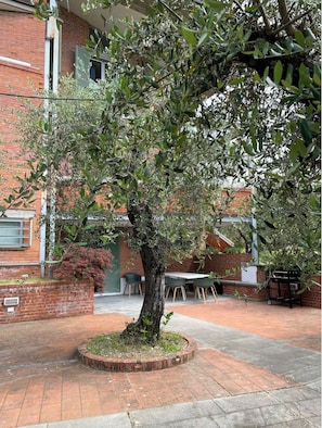 Un árbol en un patio con un muro de ladrillo y una mesa con sillas.