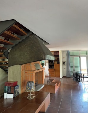 Una sala de estar moderna con chimenea, una escalera, un comedor y una estantería.