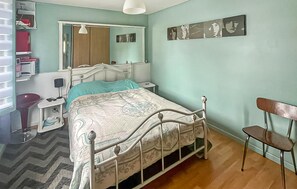A bedroom with a bed, bedside table, chair, and a mirror. - Charmante maison cosy (La Brosse-Montceaux)