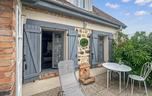 A house with a stone pillar, a small garden, and a table with chairs outside. - Charmante maison cosy (La Brosse-Montceaux)