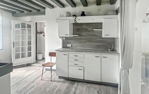A kitchen with white cabinets, a wooden countertop, and a hanging pot rack. - Charmante maison cosy (La Brosse-Montceaux)