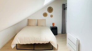 A bedroom with a bed, a nightstand, and a radiator. - Gorgeous apartment in Grand-Fort-Philippe (Grand-Fort-Philippe)