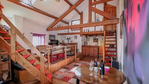 Ein rustikales Interieur mit freiliegenden Holzbalken, einer Treppe, einem Essbereich und einer Küche.
